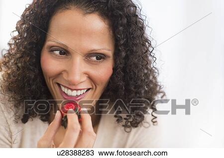Stock Image - Portrait of woman eating strawberries. Fotosearch