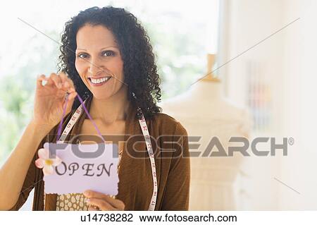 Stock Image - Portrait of woman holding open sign. Fotosearch