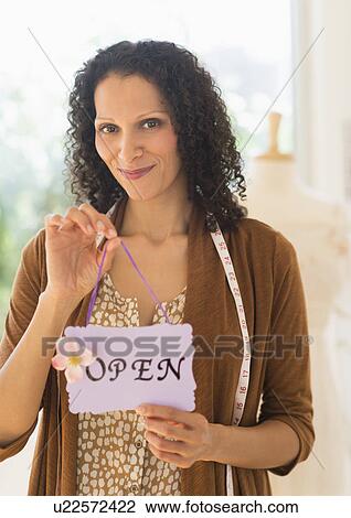 Stock Image - Portrait of woman holding open sign. Fotosearch