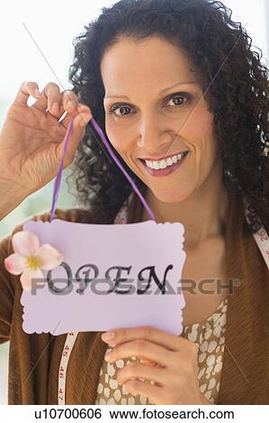 Stock Photograph - Portrait of woman holding open sign. Fotosearch