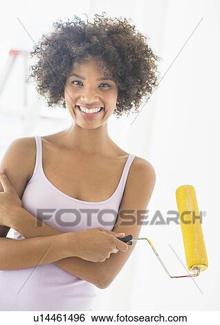 Stock Photograph - Portrait of woman holding paint roller. Fotosearch