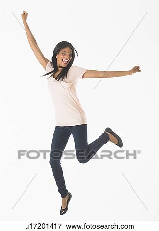 Stock Photo - Portrait of woman jumping, studio shot. Fotosearch