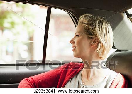 Stock Image - Portrait of woman on back seat of car. Fotosearch