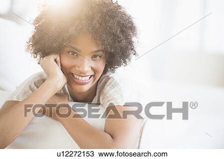 Stock Image - Portrait of woman relaxing on sofa. Fotosearch