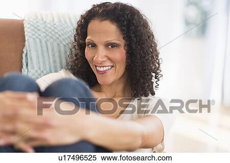 Stock Photography - Portrait of woman sitting in living room. Fotosearch