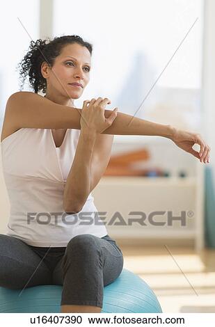 Stock Image - Portrait of woman stretching on exercise ball. Fotosearch