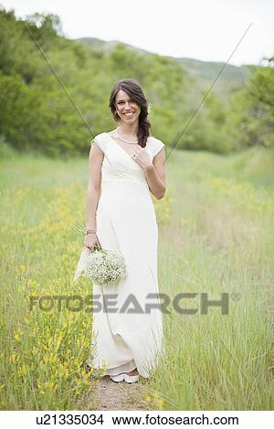 Picture - Portrait of woman wearing white dress and holding white flowers. Fotosearch