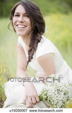 Stock Photo - Portrait of young smiling woman holding flowers. Fotosearch