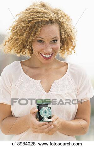Stock Photo - Portrait of young woman holding camera. Fotosearch