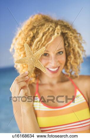 Picture - Portrait of young woman holding starfish. Fotosearch