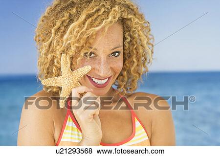 Stock Photo - Portrait of young woman holding starfish. Fotosearch