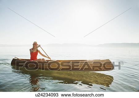 Stock Image - Portrait of young woman paddling canoe. Fotosearch
