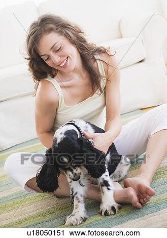 Stock Image - Portrait of young woman playing with dog. Fotosearch