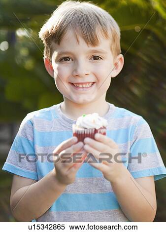 Smiling boy holding cupcake View Large Photo Image Stock Photography - Smiling boy holding cupcake. Fotosearch