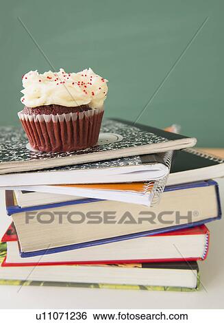 Stock Photograph - Studio shot of cupcake on stack of books. Fotosearch
