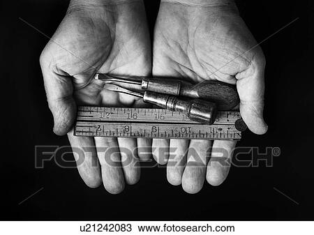 Stock Image - Studio shot of hands holding antique tools. Fotosearch