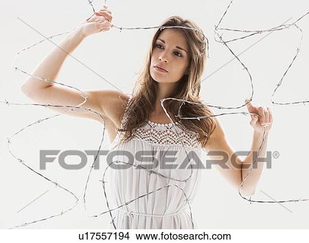 Picture - Studio shot of woman behind barbed wire. Fotosearch