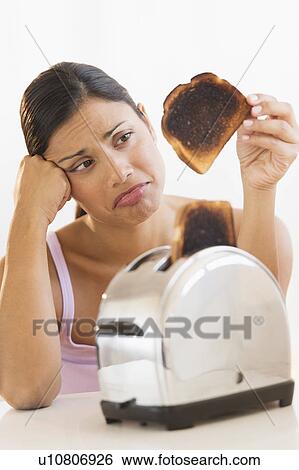 Stock Photograph - Studio shot of woman holding burnt toast. Fotosearch