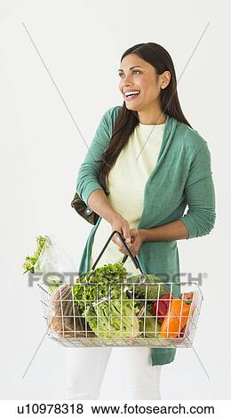 Studio shot of woman holding shopping basket with vegetables View Large Photo Image Stock Photo - Studio shot of woman holding shopping basket with vegetables. Fotosearch