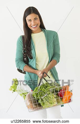 Stock Photography - Studio shot of woman holding shopping basket with vegetables. Fotosearch