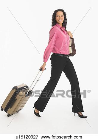 Stock Photo - Studio shot of woman walking with suitcase. Fotosearch