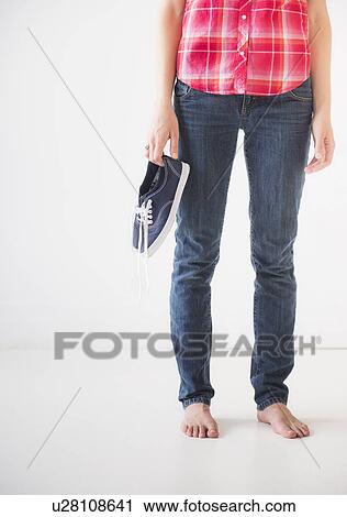 Studio shot of young barefoot woman holding shoes, low section View Large Photo Image Stock Image - Studio shot of young barefoot woman holding shoes, low section. Fotosearch