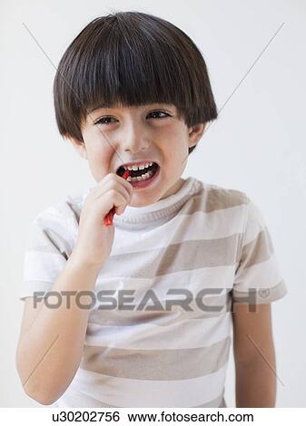 Stock Photograph - Studio Shot of young boy eating candy. Fotosearch