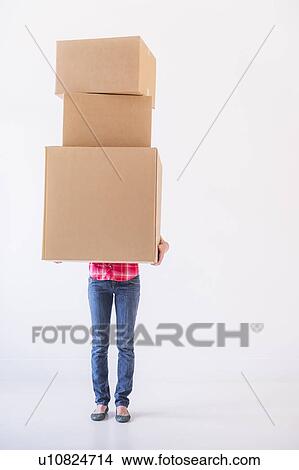 Studio shot of young woman carrying stack of boxes View Large Photo Image Picture - Studio shot of young woman carrying stack of boxes. Fotosearch