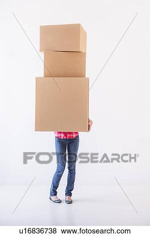 Stock Photo - Studio shot of young woman carrying stack of boxes. Fotosearch