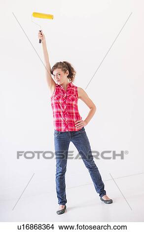 Studio shot of young woman holding paint roller View Large Photo Image Picture - Studio shot of young woman holding paint roller. Fotosearch