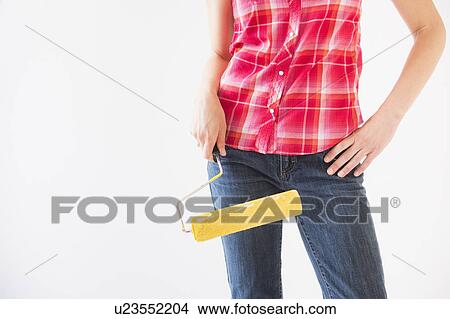 Picture - Studio shot of young woman holding paint roller, midsection. Fotosearch