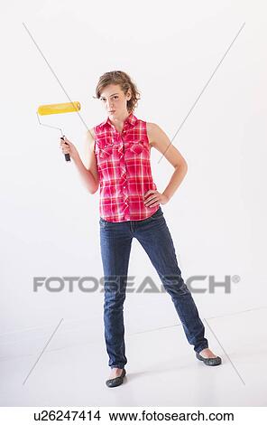Picture - Studio shot of young woman holding paint roller. Fotosearch