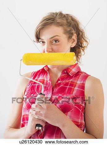 Studio shot of young woman holding paint roller View Large Photo Image Stock Image - Studio shot of young woman holding paint roller. Fotosearch