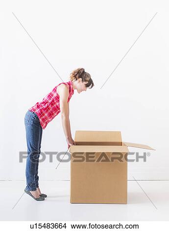 Studio shot of young woman looking into box View Large Photo Image Picture - Studio shot of young woman looking into box. Fotosearch