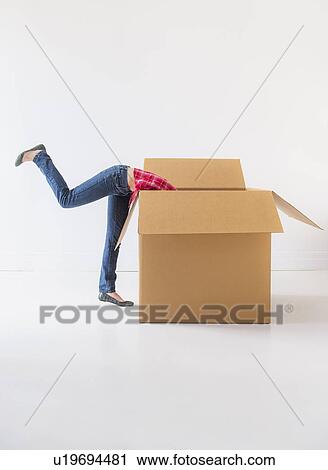 Stock Image - Studio shot of young woman looking into box. Fotosearch