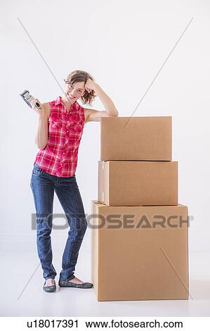 Studio shot of young woman with tape and stack of boxes View Large Photo Image Stock Image - Studio shot of young woman with tape and stack of boxes. Fotosearch