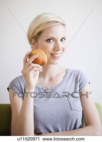 Studio Shot, Portrait of smiling woman holding apple View Large Photo Image Stock Image - Studio Shot, Portrait of smiling woman holding apple. Fotosearch