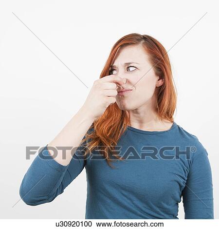 Stock Image - Studio shot, Portrait of woman holding her nose. Fotosearch