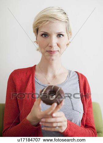 Studio shot, Portrait of woman holding chocolate covered doughnut View Large Photo Image Stock Photo - Studio shot, Portrait of woman holding chocolate covered doughnut. Fotosearch