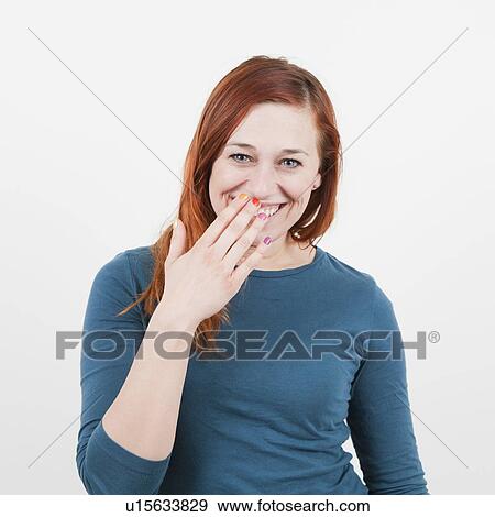 Studio Shot, Portrait of woman with long red hair covering her smile with her hand View Large Photo Image Stock Photo - Studio Shot, Portrait of woman with long red hair covering her smile with her hand. Fotosearch