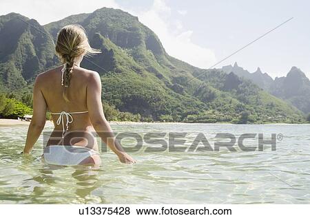 Stock Photo - Tunnels Beach, Woman walking in sea. Fotosearch