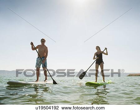 Two people standing on paddleboard View Large Photo Image Stock Image - Two people standing on paddleboard. Fotosearch