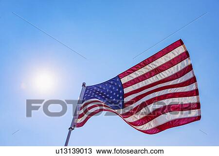 Stock Image - US flag against blue sky. Fotosearch