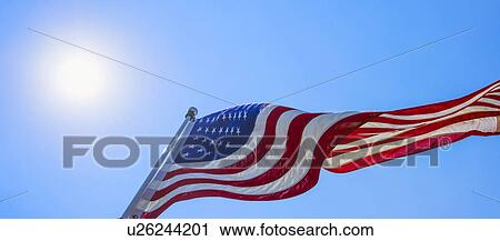 Stock Image - US flag against blue sky. Fotosearch