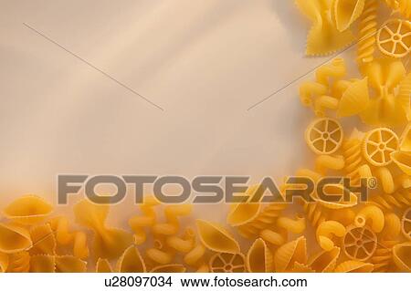 Picture - Variety of yellow pasta with blank white space in upper left corner. Fotosearch