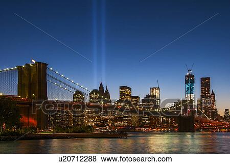 Stock Photo - View over Hudson River towards Manhattan with September 11th memorial lights and Brooklyn Bridge. Fotosearch