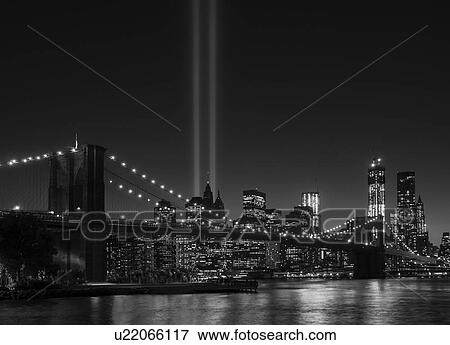 Stock Photo - View over Hudson River towards Manhattan with September 11th memorial lights and Brooklyn Bridge. Fotosearch