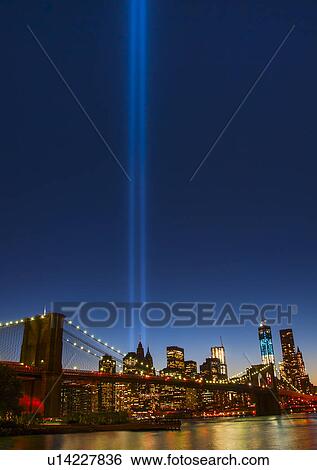 Stock Photograph - View over Hudson River towards Manhattan with September 11th memorial lights and Brooklyn Bridge. Fotosearch