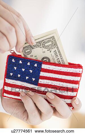 Stock Image - Woman holding banknotes and purse with american flag on it. Fotosearch
