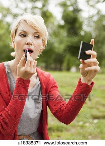 Woman holding mirror and using lipstick View Large Photo Image Stock Image - Woman holding mirror and using lipstick. Fotosearch